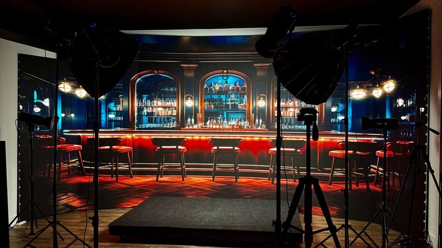 The LED wall stage showing a lounge bar scene, lit by softboxes on stands